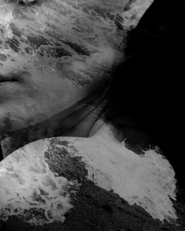 Overcome by the Sea is a black and white portrait of a woman submerged in water, eyes closed, with waves gently caressing her face.