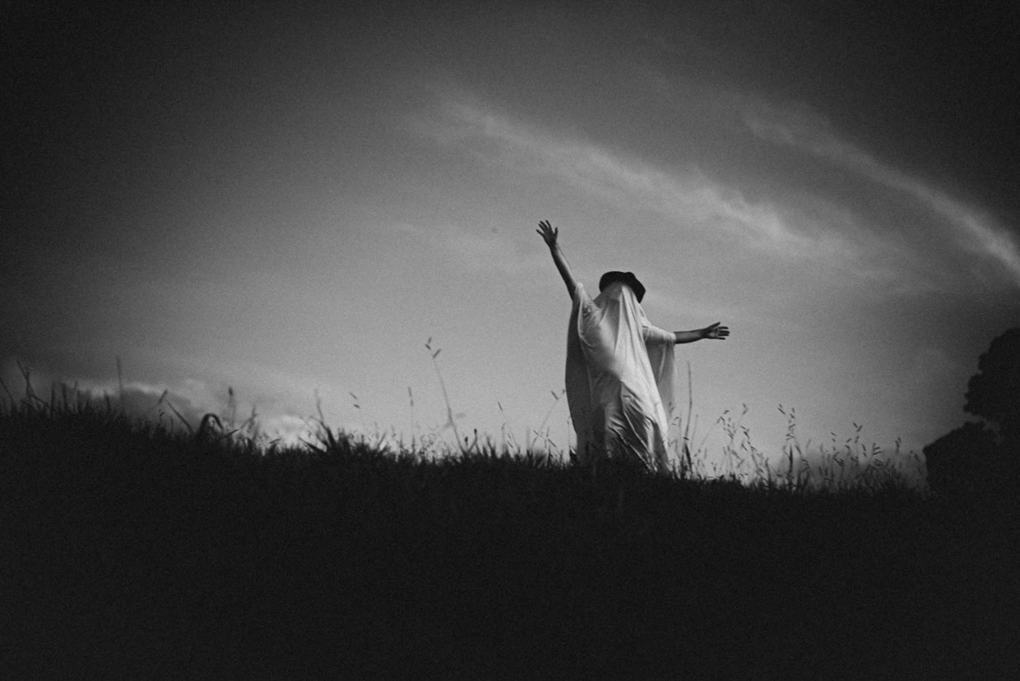 Free-spirited woman in a ghost costume, joyfully embracing the freedom of an open meadow
