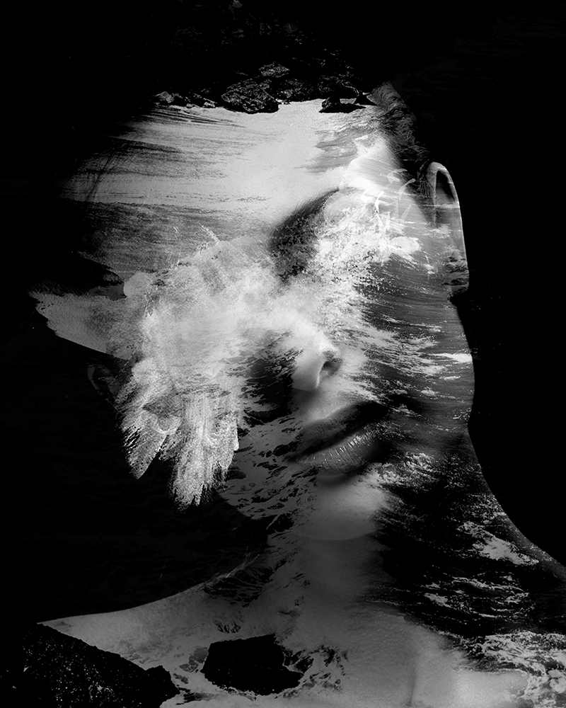 Submerged in the Waves is a black and white portrait of a woman blended with waves crashing onto a reef, from a different angle, her face obscured by the foam